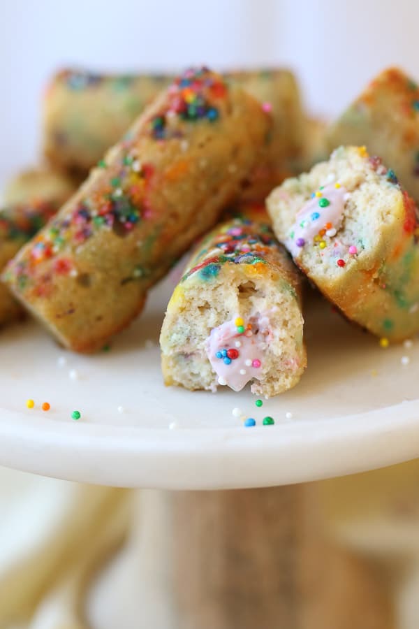 close up image of gluten free rainbow twinkies filled with strawberry protein cream on a white plate