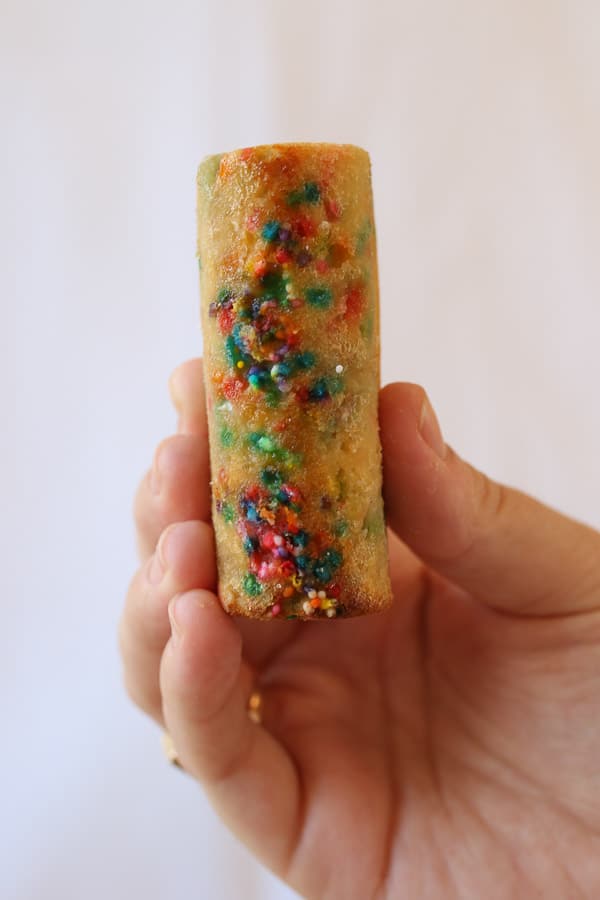 birds eye view of a hand holding a gluten free rainbow twinkie 