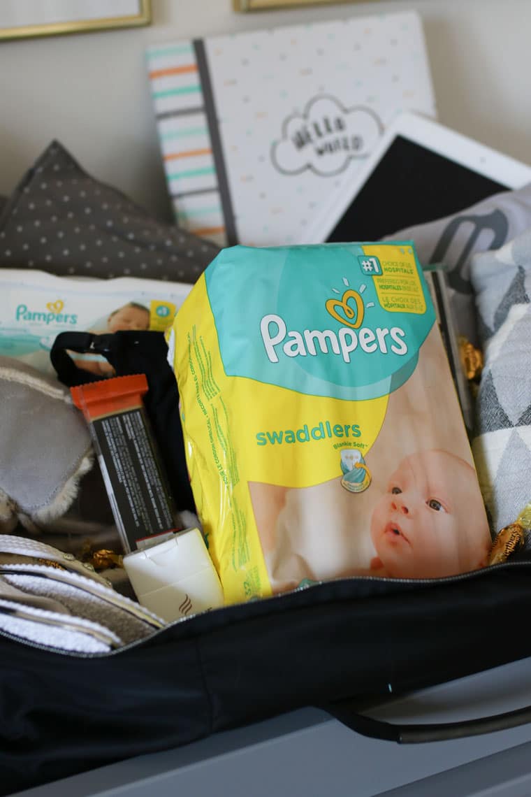 A hospital bag with pregnancy essentials with a close up on the pack of pampers.