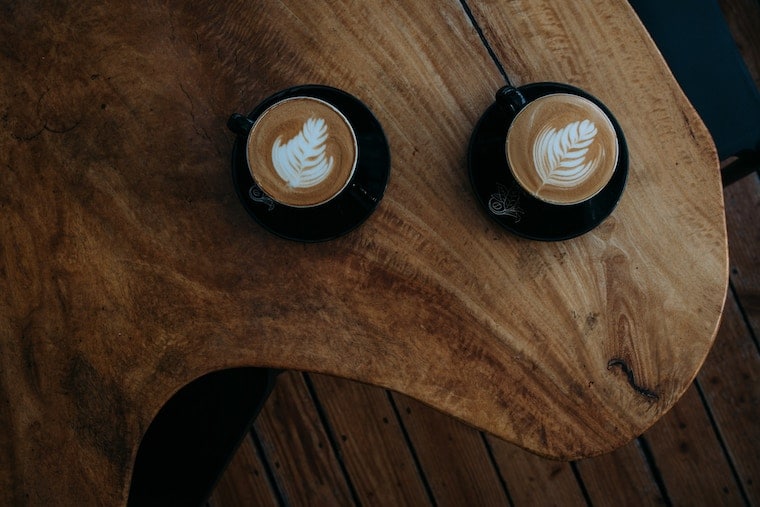 Two lattes on a wooden table.