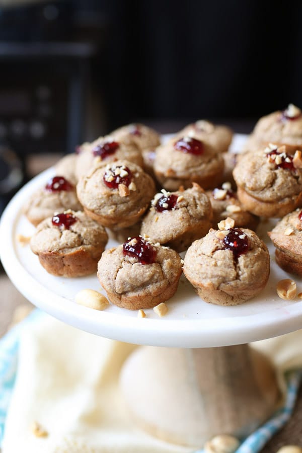 A white plate with blender muffins with jam on top and peanuts.