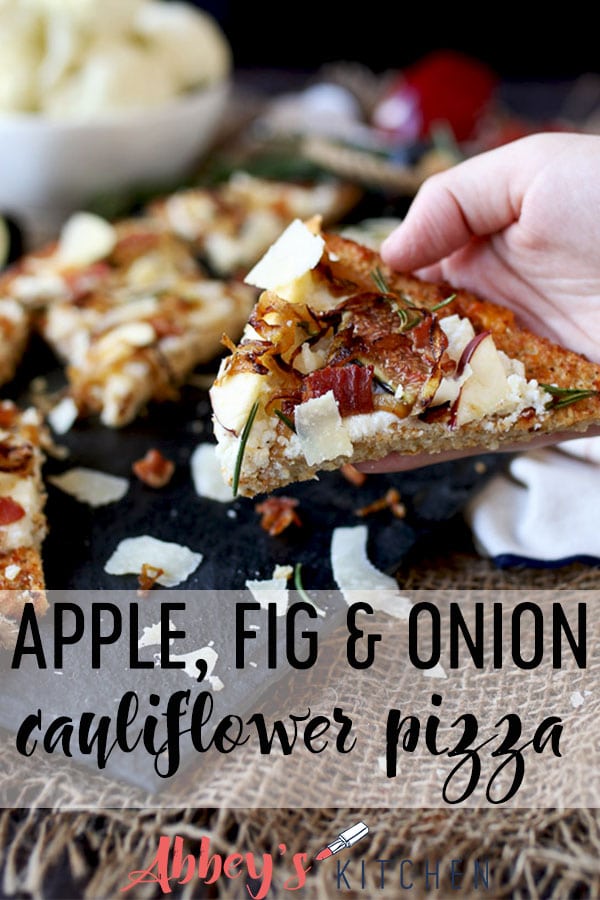 pinterest image of hand holding a slice of apple, fig and onion cauliflower pizza flatbread with text overlay