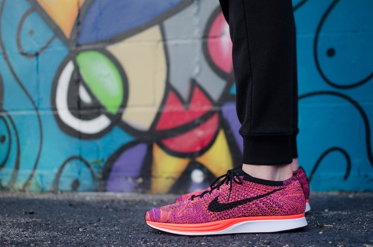 A pair of feet wearing pink nike shoes.