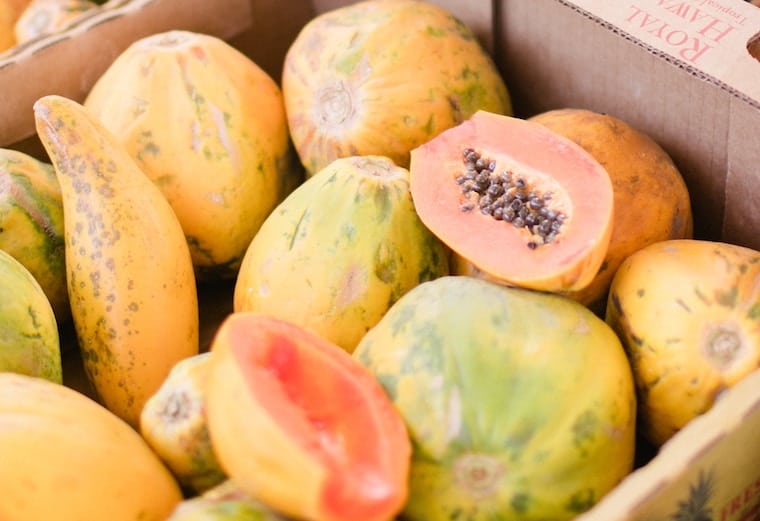 Box of papayas with one cut open. 
