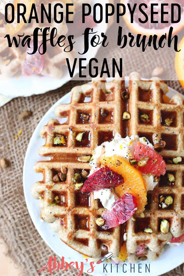 Overhead shot of a plate of vegan orange poppyseed waffles topped with yogurt, orange segments and crushed pistachios.