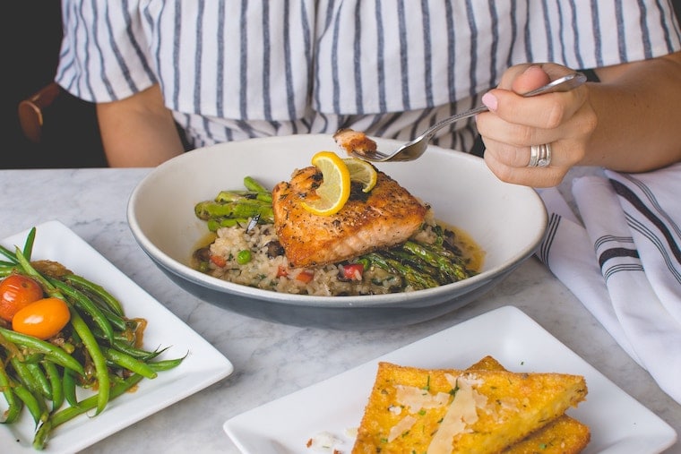 Person holding a fork eating salmon.