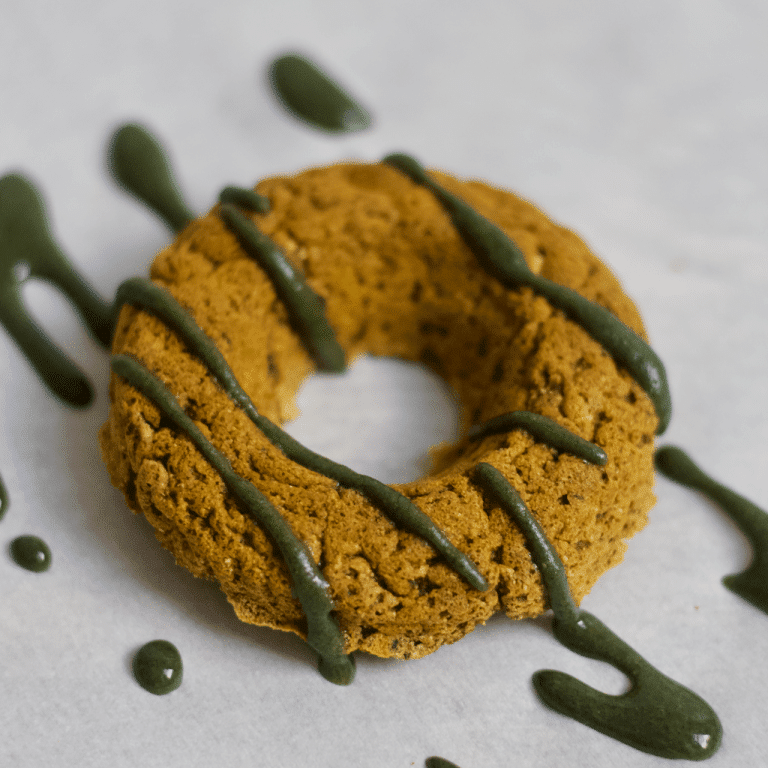 A vanilla matcha protein donut with glaze drizzled on top.