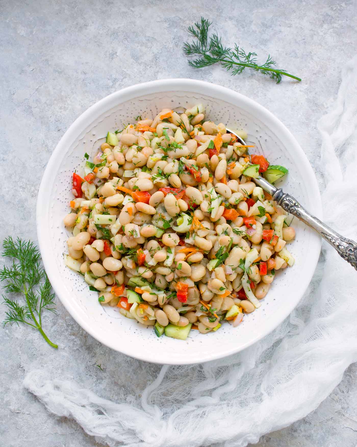 Herbed white bean salad in a white bowl. 