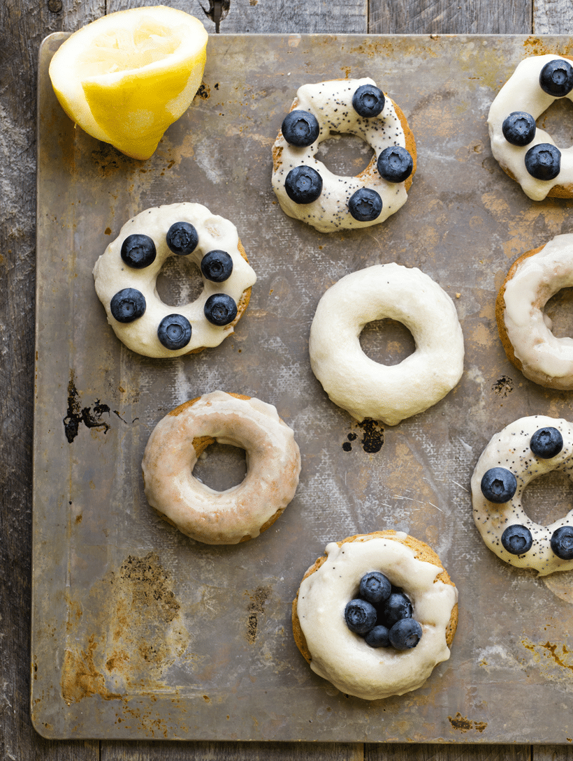 Overhead image of 7 lemon poppyseed donuts with blueberries on top.