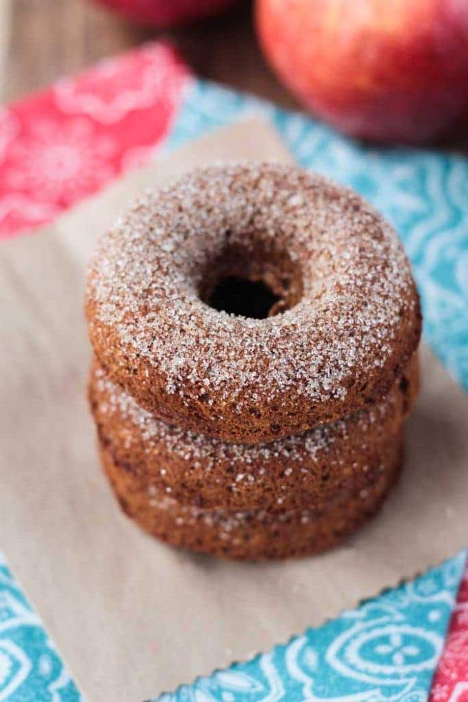 A close up of a stack of three baked apple cider donuts.
