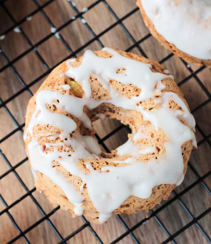 A close up photo of a peaches and cream donut on a cooling rack.