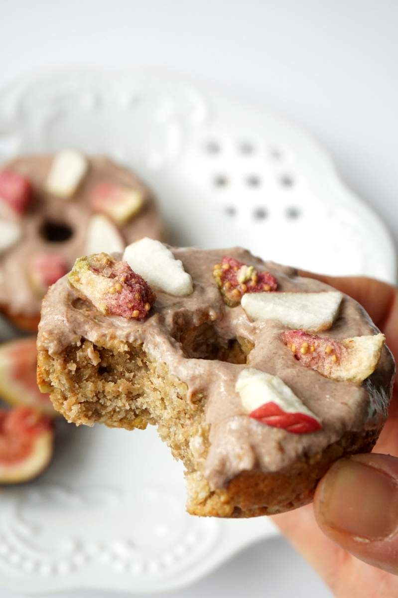 An apple and fig donut with a bite taken out of it.