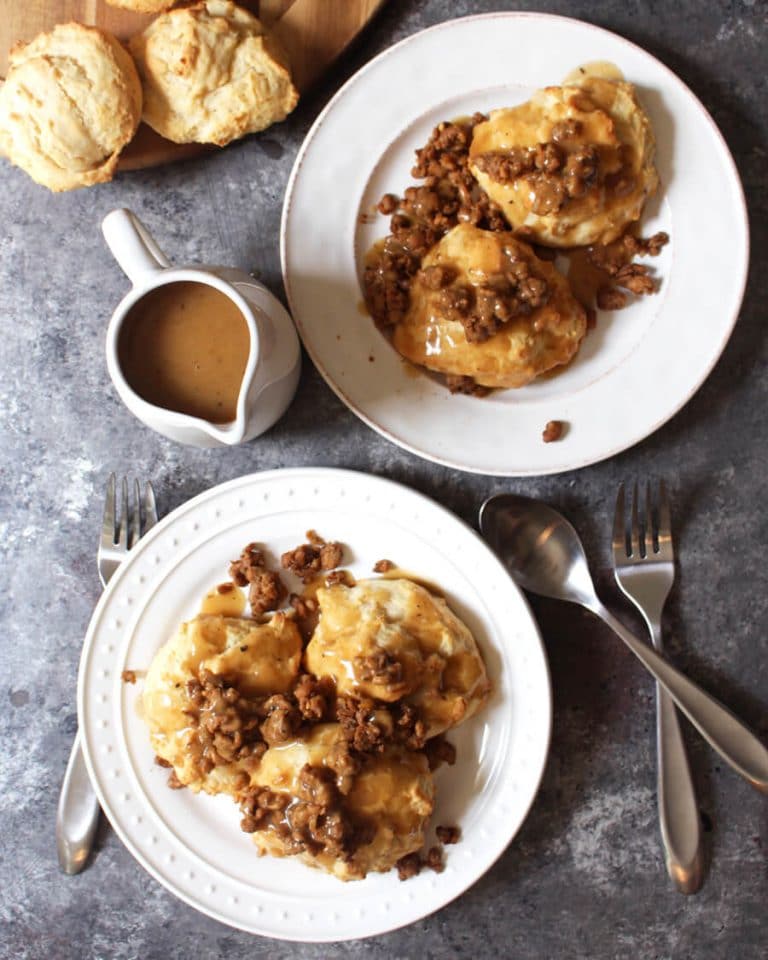 Vegan sausage and biscuits with gravy on white plates.