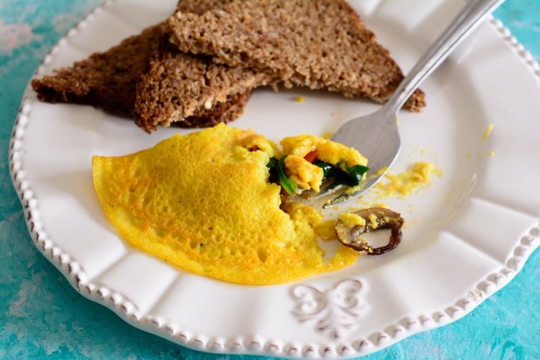 Ackee omelette on a white plate served with whole grain bread. 