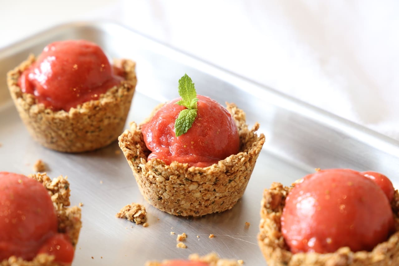 Strawberry sorbet in almond granola cups topped with mint sprig. 