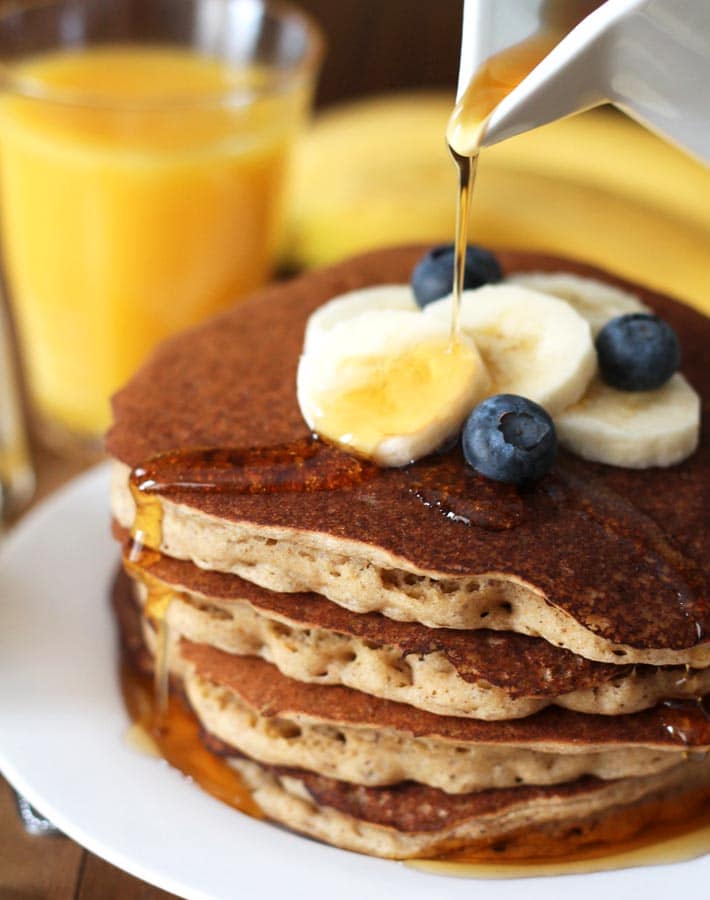 Banana pancakes topped with blueberries, sliced bananas and maple syrup. 