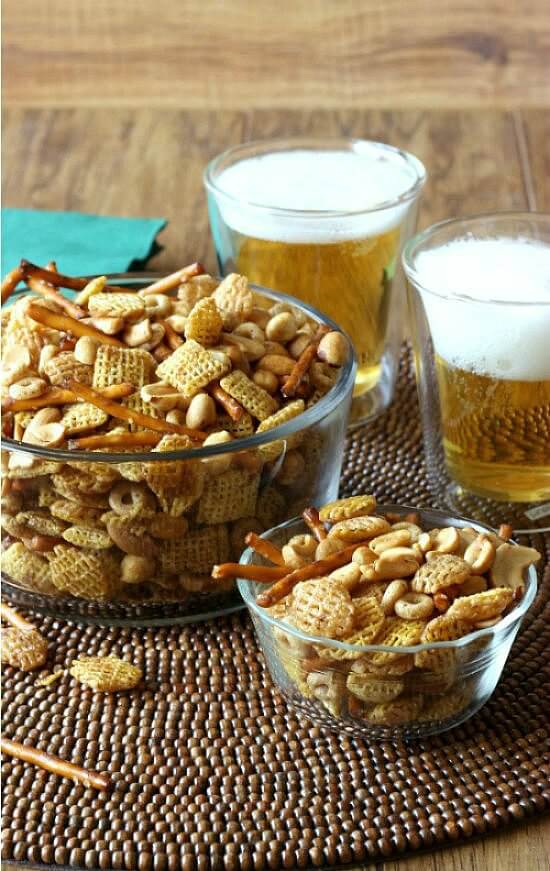 A bowl of trail mix next to beer. 