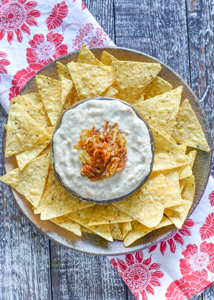 Vegan onion garlic dip on a platter with tortilla chips. 