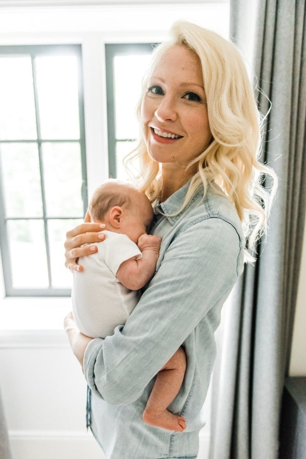 Abbey Sharp holding a baby next to a window.