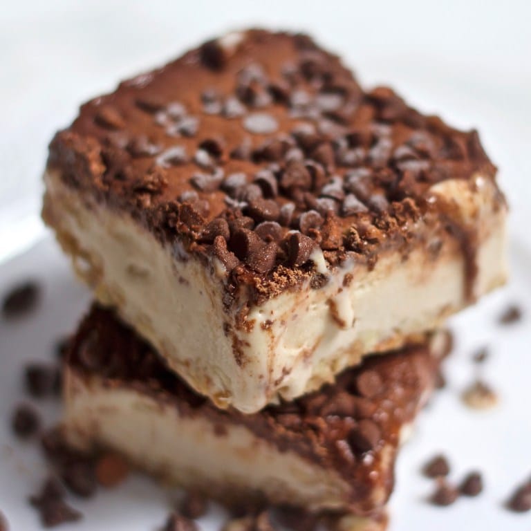 Two vegan vanilla almond ice cream cakes stacked on top of one another on a white plate, garnished with additional chocolate chips