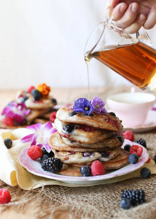 Stack of elderflower pancakes topped with edible flowers. 