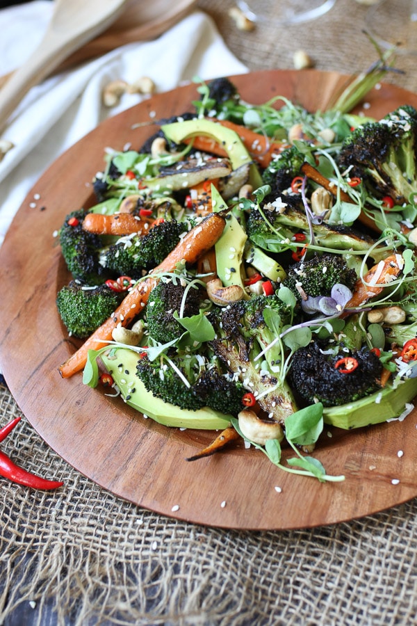 Grilled broccoli and carrot salad on a wooden plate.