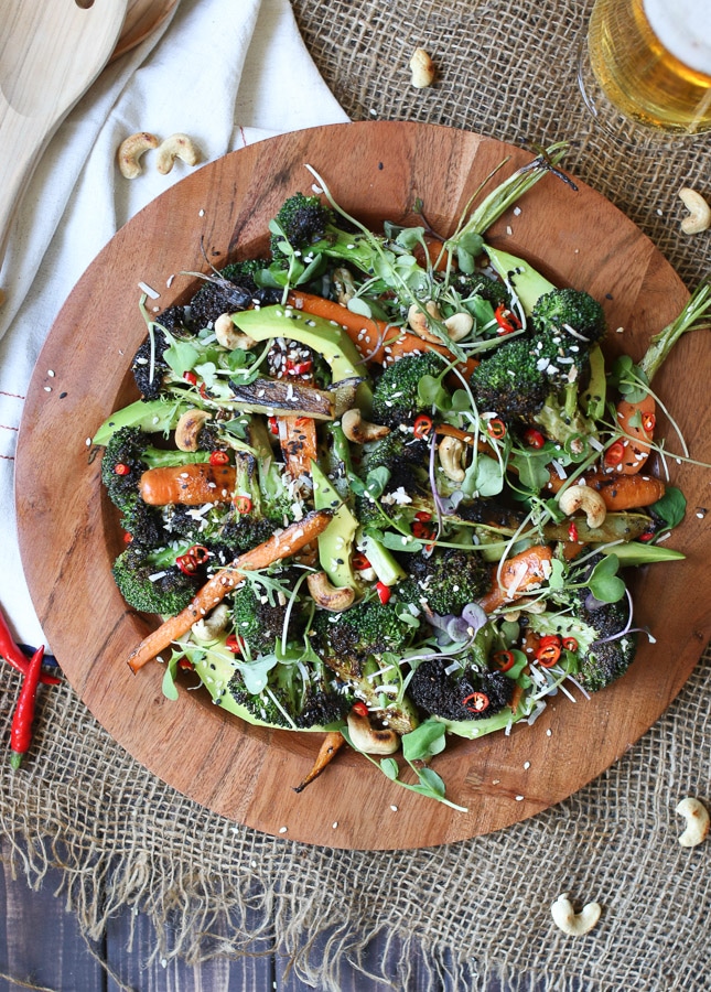 Grilled broccoli and carrot salad on a wooden plate.