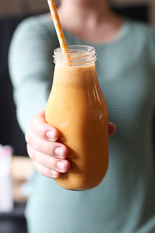 Person holding a glass of carrot cake lactation smoothie.