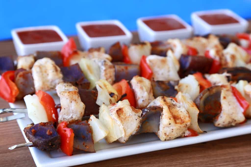 close up of red white and blue kebabs with dipping sauces