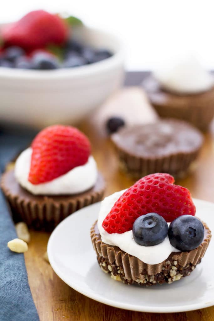 close up of gluten free and vegan no bake chocolate cheesecakes topped with berries 