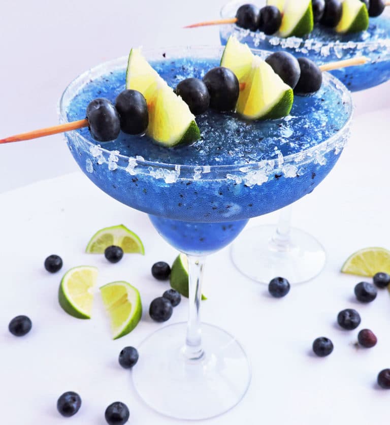 close up of frozen blueberry and lime margarita topped with blueberries and lime