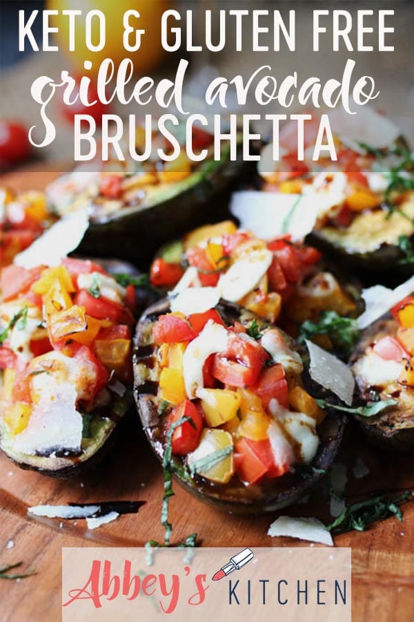 pinterest image of Grilled avocado bruschetta served on a wooden plate topped with herbs, parmesan and balsamic with text overlay. 