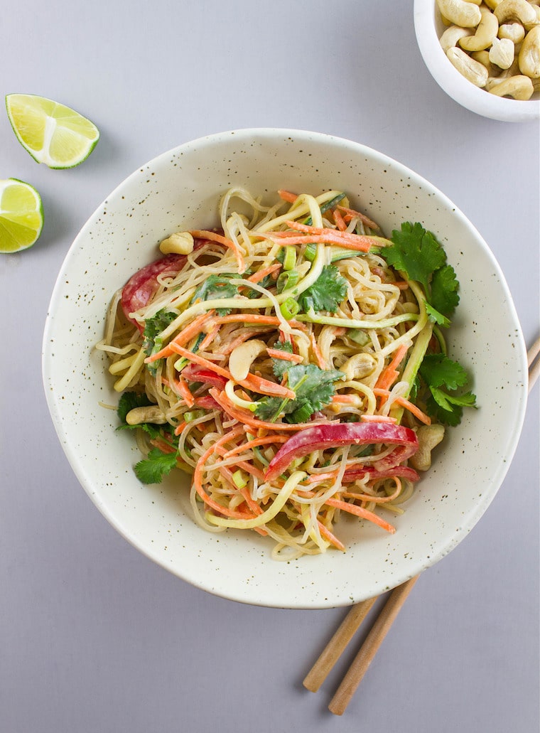 birds eye view of raw pad thai topped with herbs in a white bowl