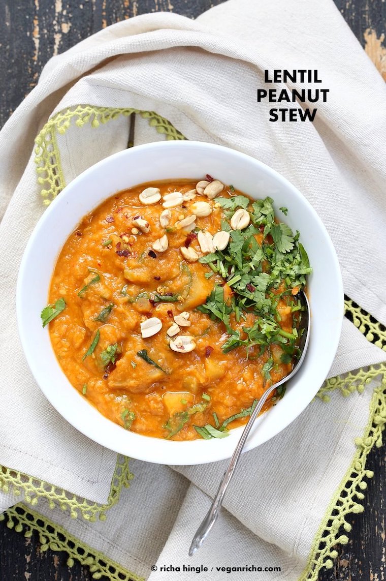 birds eye view of vegan african peanut lentil stew in a white bowl topped with herbs