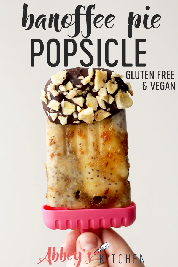 pinterest image of Hand holding a banoffee pie popsicle coated in chocolate and crushed banana chips with text overlay