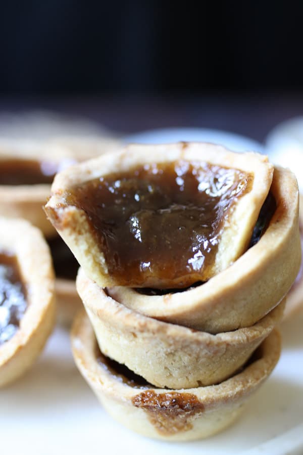 a pile of plant based butter tarts with a bite taken from one butter tart 