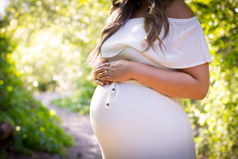 A woman holding her pregnancy bump referring to the question "Can you diet while pregnant?".