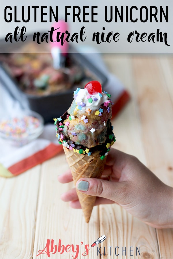 hand holding unicorn nice cream in a cone garnished with whipped cream