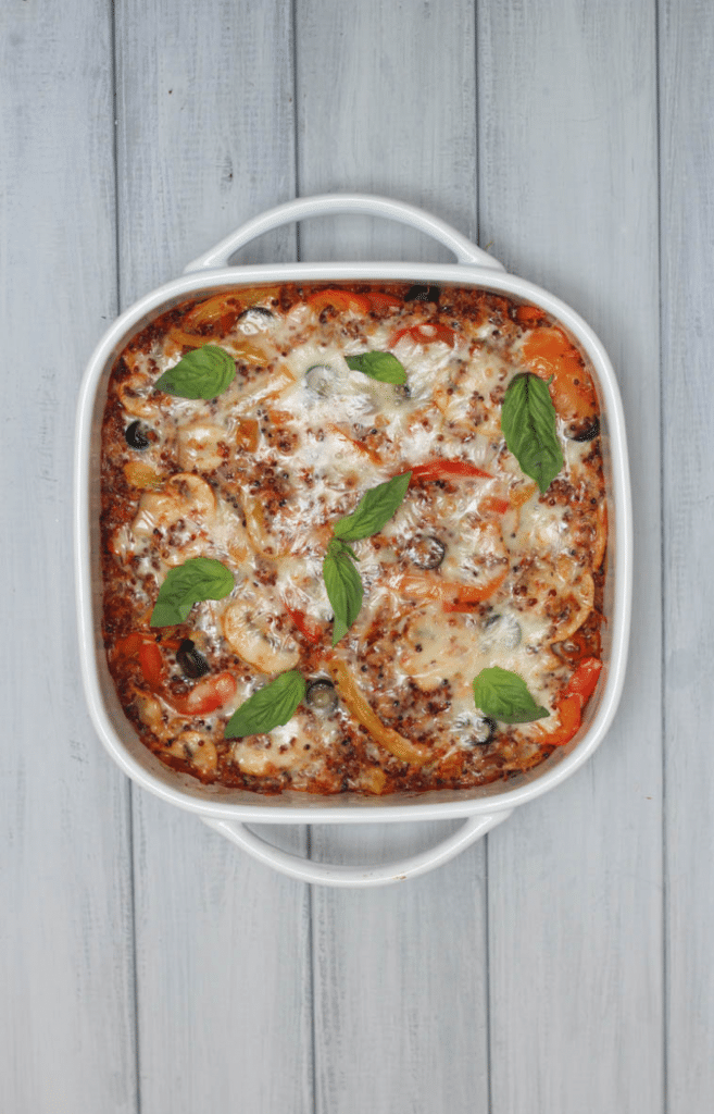 birds eye view of pizza quinoa casserole in a white dish garnished with fresh herbs