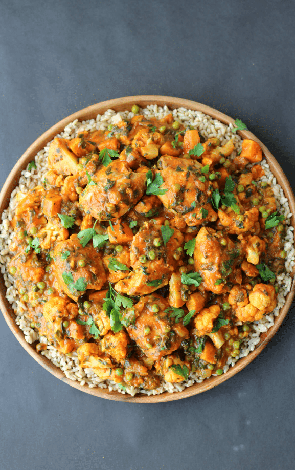 birds eye view of paleo chicken curry garnished with fresh herbs in a wooden bowl