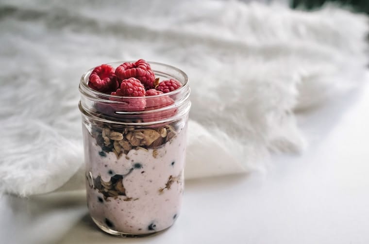 Yogurt and granola parfait in a mason jar topped with raspberries.