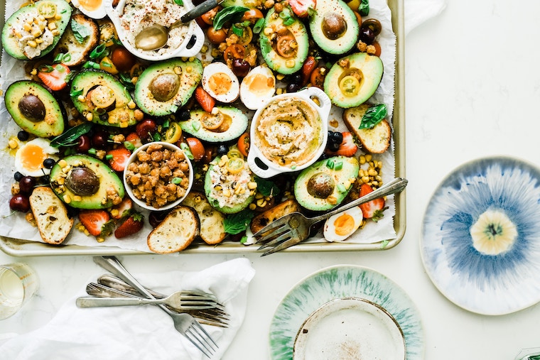 birds eye view of a sheet pan containing various foods on a white background