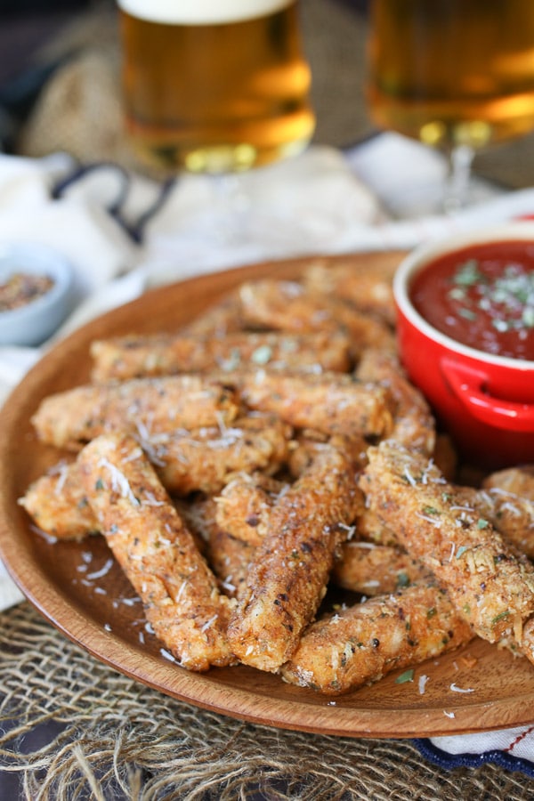 Mozzarella sticks served on a wooden plate.