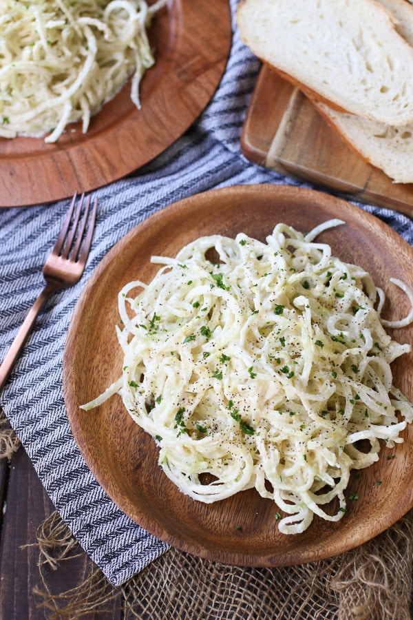 birds eye view of vegan paleo keto pasta alfredo garnished with herbs on a wooden plate