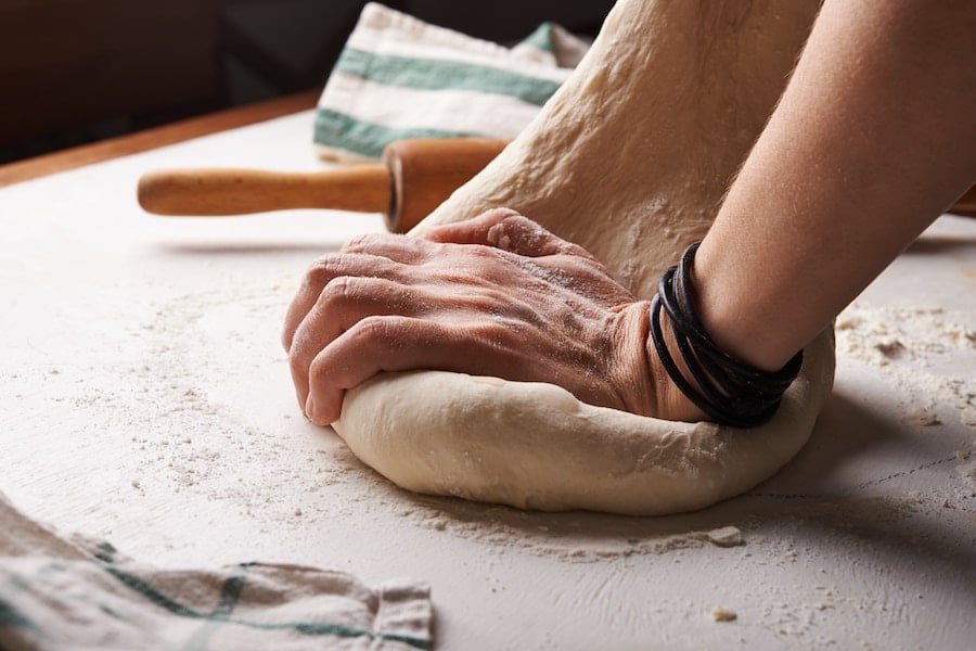 person kneading a ball of dough