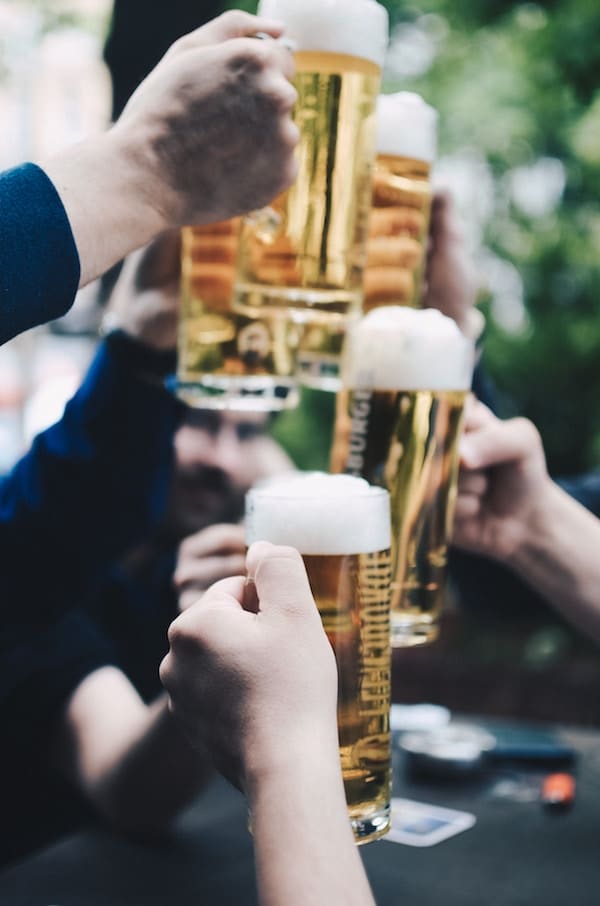 Multiple people raising glasses of beer.