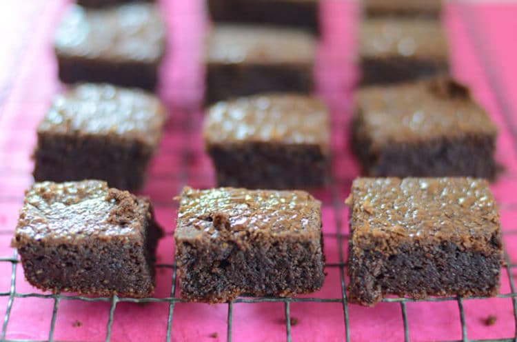 close up of keto brownies on a cooling rack on a pink surface