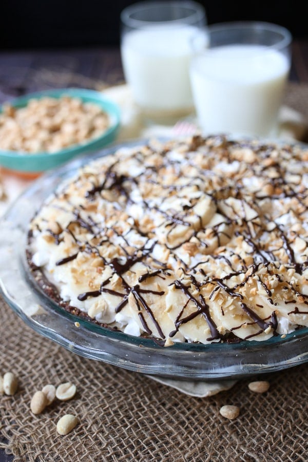 frozen peanut butter pie in a glass dish topped with chocolate and chopped peanuts