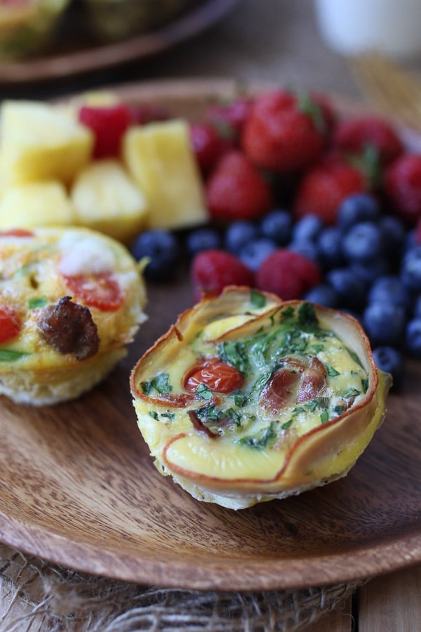 egg cups on a wooden board next to fruit