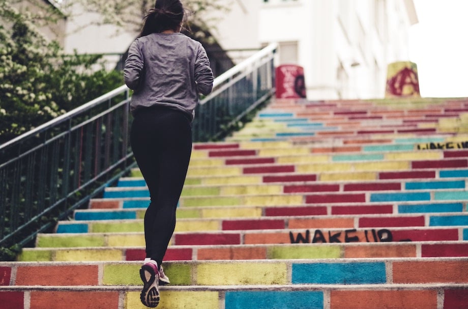 Woman who does intermittent fasting and working out seen running up a flight of stairs. 